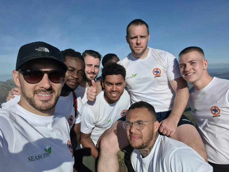 The Seasons FC team in Seasons T-shirts at the top of a peak