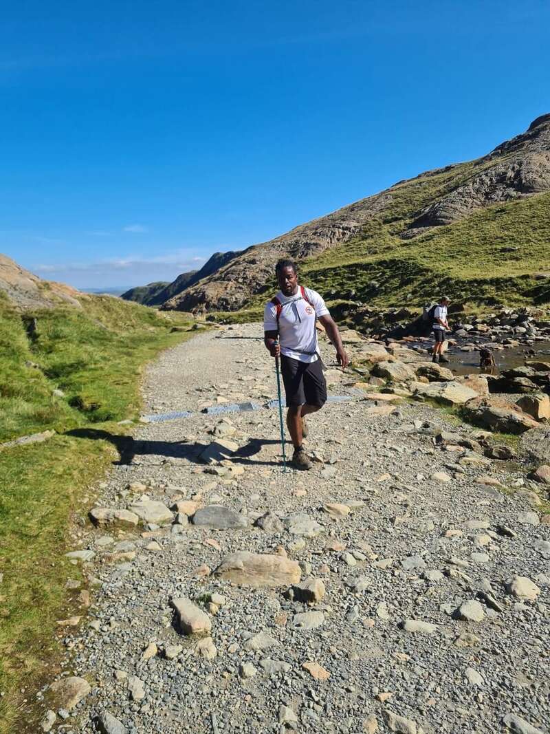 A walker with a trekking pole on a rocky mountain path