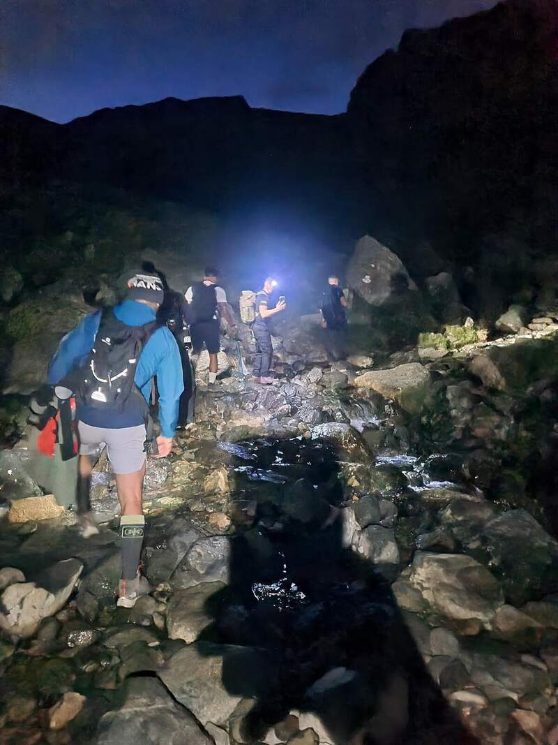 The team crossing a rocky stream in the dark with head torches