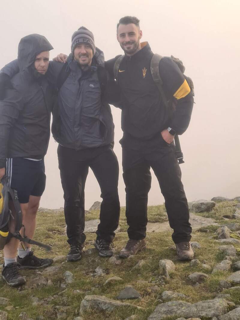 Three walkers standing together in the mist at the summit